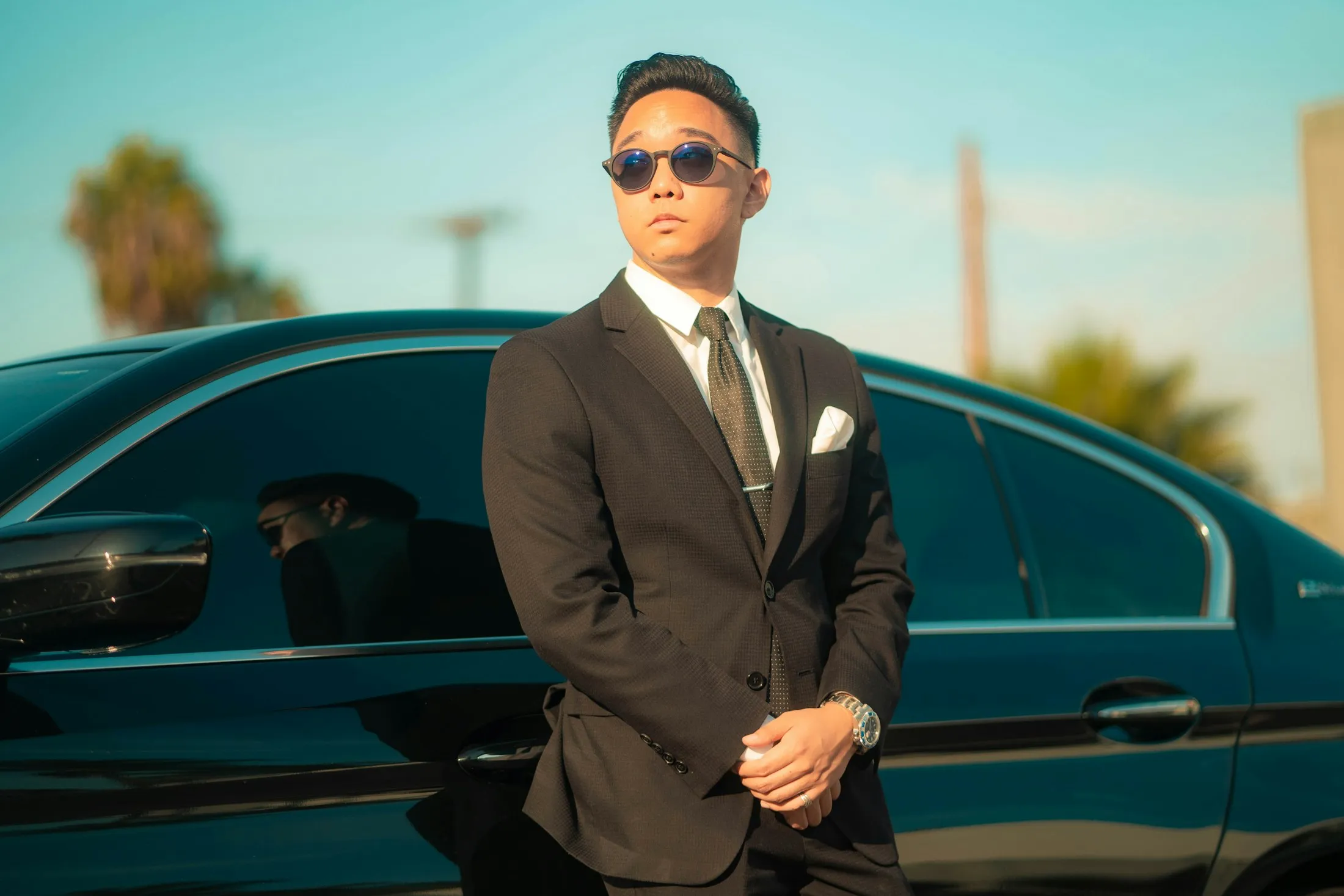 Chauffeur professionnel en costume devant une berline noire